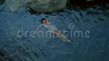 迷人的女人放松在<strong>清澈</strong>的<strong>河水</strong>空中拍摄。 年轻女子在河中无人驾驶的视野中游泳。 放松和享受
